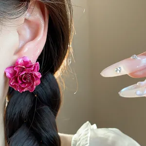 Close-up detail of a vibrant fuchsia resin rose stud earring worn on an ear for a sweet look