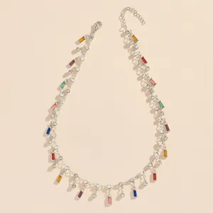Detail view of colorful rhinestone square pendant necklace on a beige background