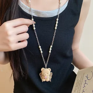 Detail of cute flocked teddy bear pendant with wings on a pearl and steel necklace.