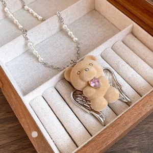 Close-up of cute flocked bear pendant with pink heart zircon and pearl necklace chain