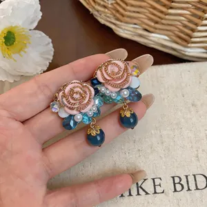 Detailed view of French vintage resin rose earrings with blue crystals and pearls