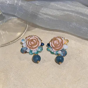 Close-up of French retro pink resin rose stud earrings with blue bead accents