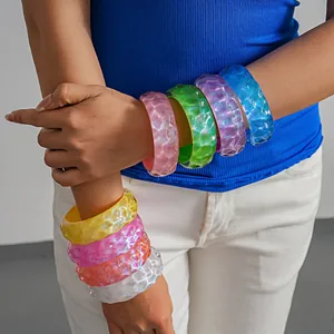 Detail view of colorful iridescent wrinkled resin bangles styled on a model's arm