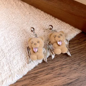 Detailed view of cute flocking teddy bear earrings with pink heart and silver angel wings.