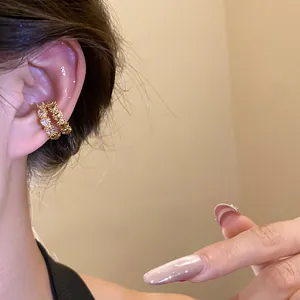 Close-up of an elegant double-layer gold ear cuff with sparkling cubic zirconia on ear