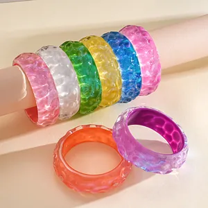 Detailed view of colorful iridescent resin bangles with a unique textured ripple surface.