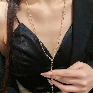 Elegante collana a Y dorata con pendenti a cuore e perline lucide su una modella