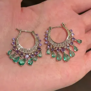 Close-up of luxury hoop earrings with purple and green zircon teardrop tassels