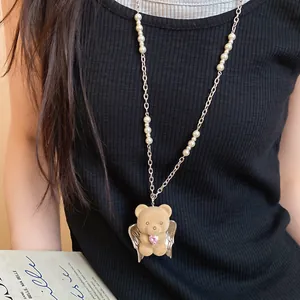 Detail showing flocked teddy bear pendant with wings and pink zircon heart on pearl necklace