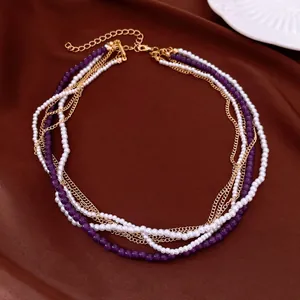 Elegante collana multistrato con perle bianche, perle di vetro viola e catenine dorate.