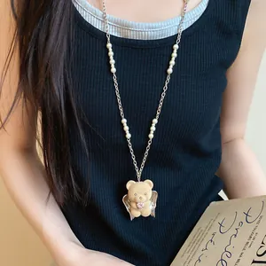Detail view of a flocked bear pendant necklace with pearls and a pink heart zircon.