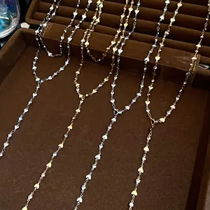 Vista dettagliata di collane a Y a forma di cuore con strass in oro e argento.