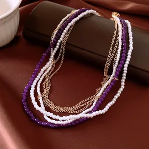 Dettaglio di collana a più strati con perle viola e catena d'oro
