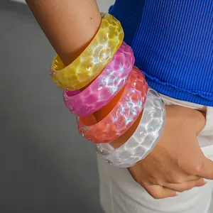 Close-up of colorful iridescent resin bangles with pleated texture on model's arm