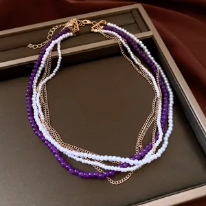 Vista dettagliata di collana multistrato con perle viola, bianche e catene dorate