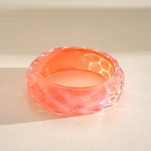 Close-up of iridescent pleated resin bangle with vibrant orange and pink gradient finish