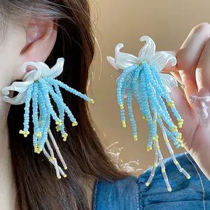 Close-up of French flower tassel earrings featuring vibrant blue and yellow beadwork.