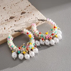 Detail of colorful beaded hoop earrings with dangling pearls in a vibrant vacation style.