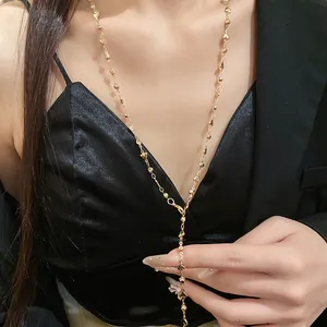 Vista dettagliata di una collana a Y dorata con ciondoli a cuore indossata da una modella