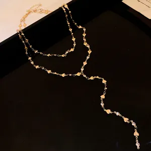 Dettaglio della collana a Y dorata a doppio strato con ciondoli a cuore e strass