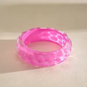 Macro view of the pink resin bangle showing unique pleated wave patterns and glossy finish.