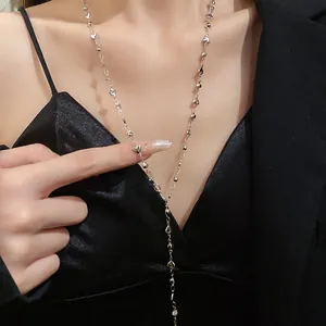 Primo piano di una collana a Y minimalista con cuore d'argento su una modella donna