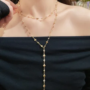 Primo piano della collana a Y a doppio strato in oro con ciondoli a cuore e strass.