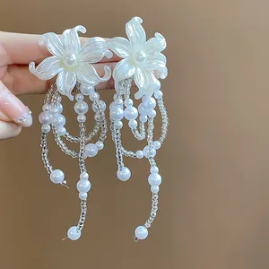 Close-up detail of elegant white flower earrings with long pearl bead tassels