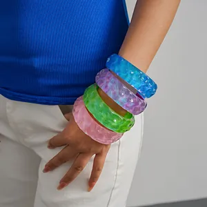 Detail shot of colorful resin bangles with wrinkled texture worn on a model's wrist