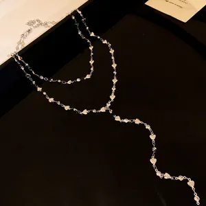 Elegante collana a Y a doppio strato con cuori e strass su un lussuoso sfondo nero opaco