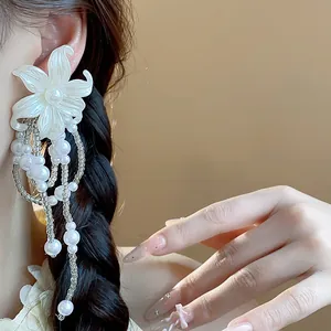 Close-up of elegant white floral tassel earrings with pearl details on a model