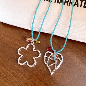 Dettaglio dei pendenti traforati a fiore e cuore con cordoncini intrecciati blu chiaro
