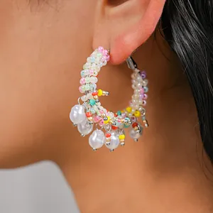 Close-up of colorful beaded hoop earrings with pearl charms, dopamine style jewelry