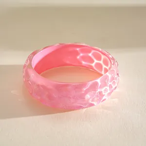 Close-up of vibrant pink iridescent resin bangle with a unique pleated ripple texture