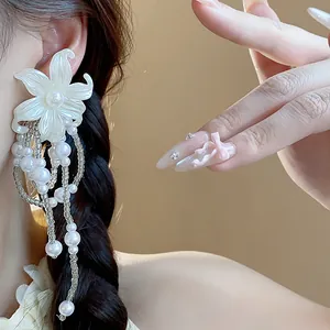 Close-up view of elegant white flower earrings with dangling pearl tassels on model