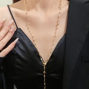 Primo piano di un'elegante collana a Y dorata con pendenti a cuore e cristalli lucenti