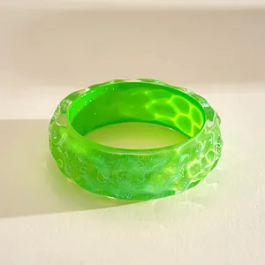 Macro view of bright green pleated resin bangle with iridescent marbled finish