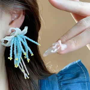 Detailed view of elegant blue beaded tassel flower earrings with resin flower base on model