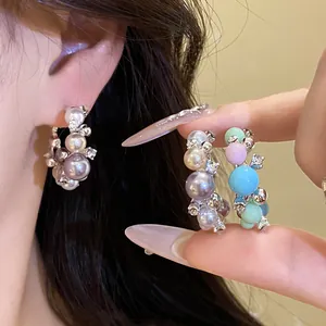 Close-up of colorful pearl hoop earrings with rhinestone details on a model's ear