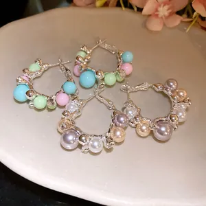 Macro view of elegant silver hoop earrings with colorful pastel beads and pearls on a dish