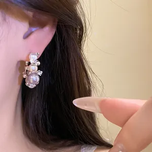 Close-up of elegant silver needle hoop earring with lustrous pearls and rhinestones