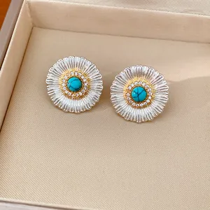 Macro view of floral silver stud earrings featuring turquoise center and zircon accents