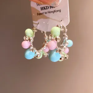 Macro detail of colorful pastel bead hoop earrings with silver needles and crystal accents