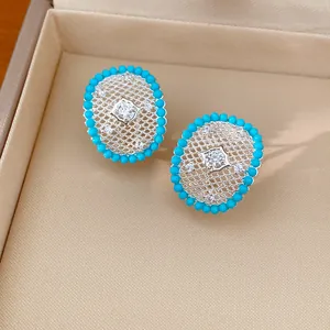 Detailed view of elegant oval hollow earrings with turquoise-colored beads and zircons