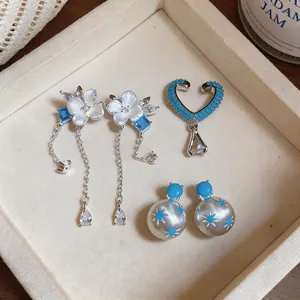 Vista detallada de elegantes pendientes de borla de flores y aretes con patrón de estrellas.