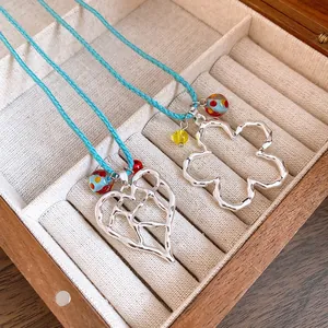 Primo piano di eleganti pendenti a cuore e fiore in argento traforato in un portagioie in legno.