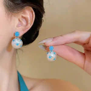 Primer plano de pendientes de plata de estilo veraniego con esferas de estrellas azules