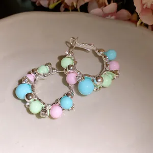 Close-up of elegant silver hoop earrings with pastel beads and sparkling crystals