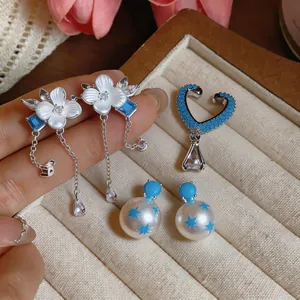 Primer plano de pendientes de flores de circón y perlas de estrellas azules en bandeja.