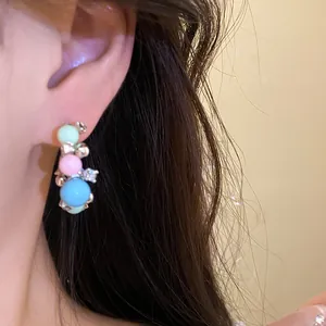 Detailed view of pastel beaded earrings with silver accents worn on ear